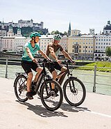 2 Radfahrer am Salzkammergutradweg in Salzburg, im Hintergrund die Festung und der Fluß Salzach