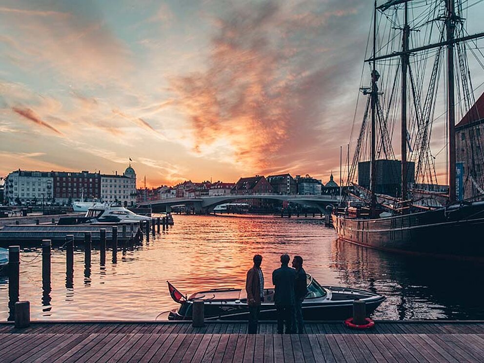 Hafen mit Booten und großen Segelschiffen in der Abenddämmerung