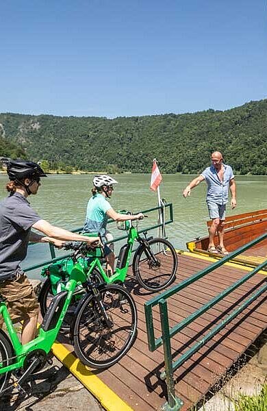 cyclists enter the ferry at the Danube River