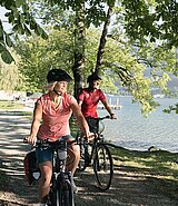 a couple cycles nearby the lake on a shady path