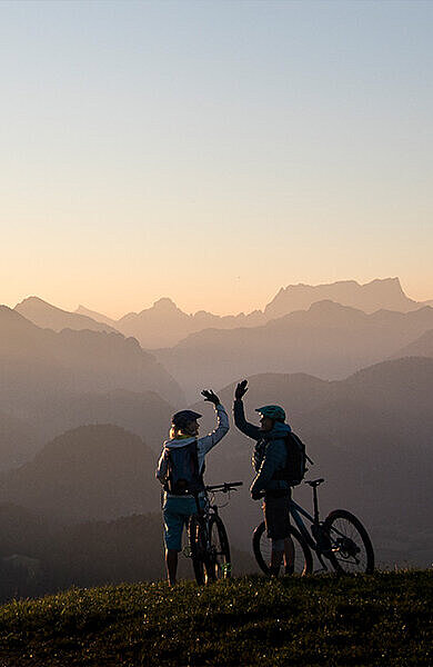 2 Mountainbiker in der Abenddämmerung vor herrlicher Bergkulisse