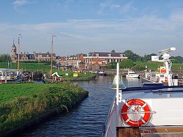 Ein Schiff fährt auf einem Fluss, im Hintergrund die Stadt Willemstad