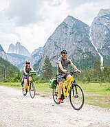 2 Radfahrer am Schotterweg, im Hintergrund Berge