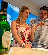 Mann und Frau verkosten Frankenwein. Sie halten Weingläser in den Händen, Bocksbeutelflaschen stehen davor.
