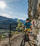 2 Biker am Felsvorsprung, ein Zaun als Absturzsicherung, bei Sonnenschein